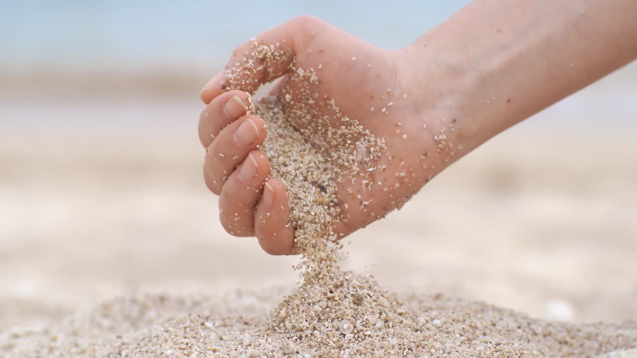 Sand falling from hand in slow motion on a beach. Vacation and travel concept. Shot on super slow motion camera 1000 fps.
