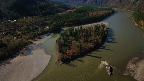 flying over a beautiful mountain river in altai with a small island overlooking the forest and mountains