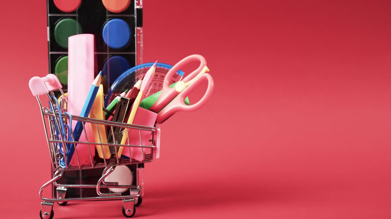 cerca del carrito de compras con artículos escolares y pinturas con espacio de copia en fondo rojo