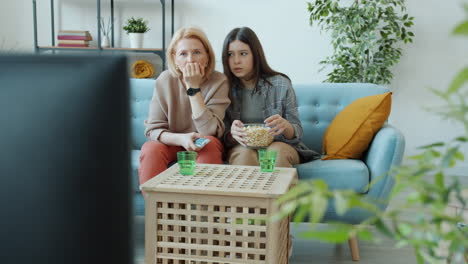 mother and daughter watching tv and eating popcorn