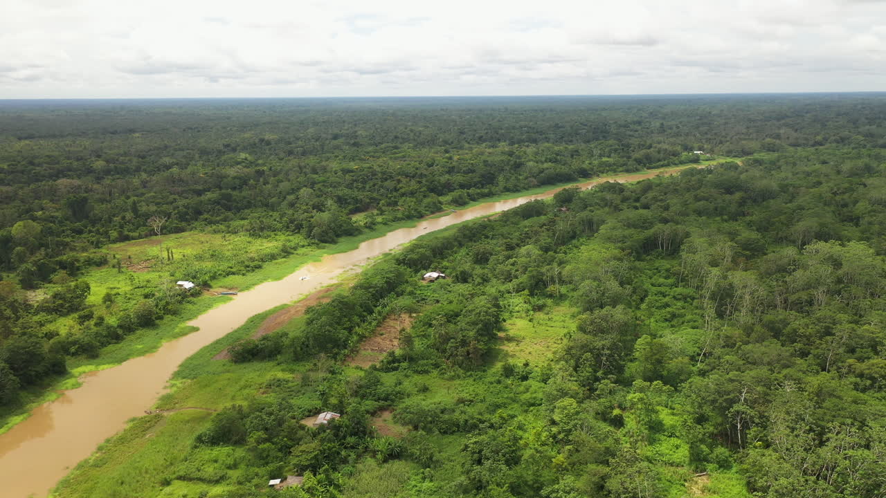 toma aérea giratoria cinematográfica del río amazonas y la selva tropical con algunos edificios pequeños en el bosque en perú