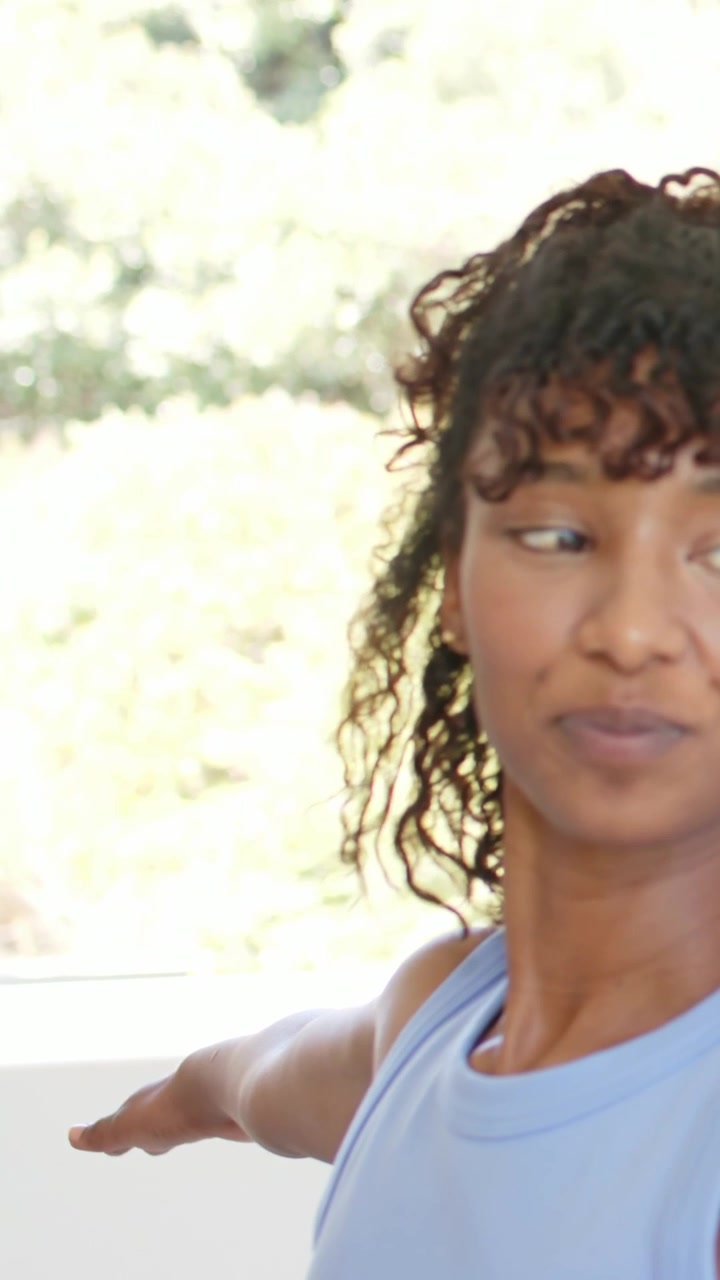 Vertical video: Woman blue top extending arm near window right arm entering stretching, copy space