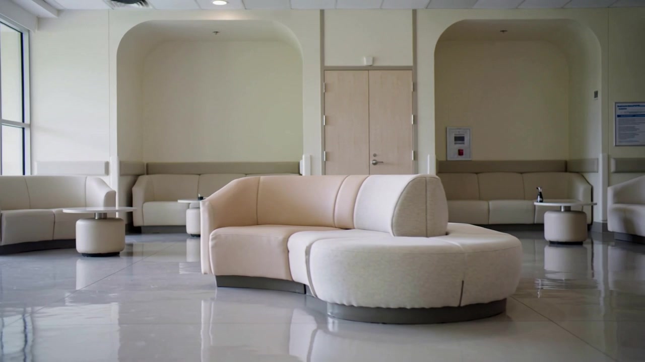 Shifting camera revealing curved modular sofa in waiting area with windows, ottomans, glossy floor