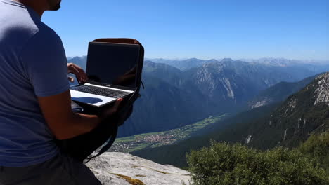 person working on a laptop with a stunning mountain and valley view