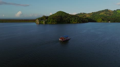 ferry cruising on hatillo dam reservoir at sunset, dominican republic. aerial drone orbiting, copy space
