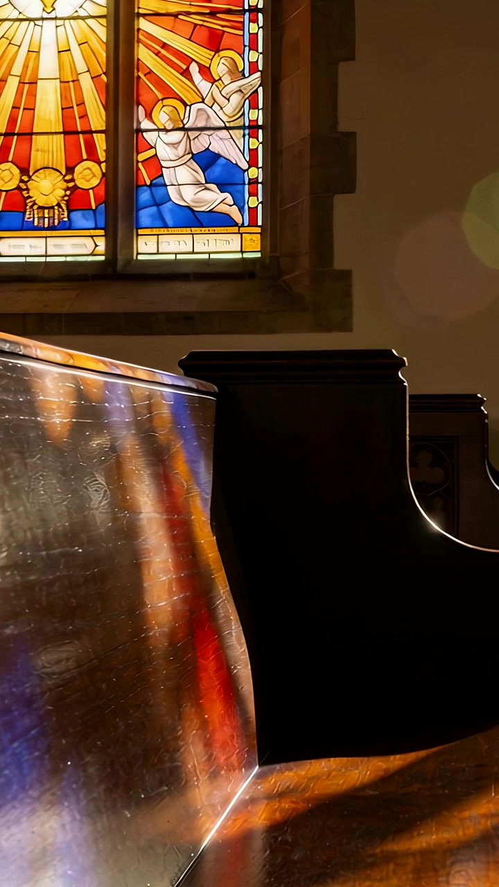 Video verticale: Il sole che filtra fa sì che la telecamera si muova sopra un banco in chiesa, mostrando i colori delle vetrate.