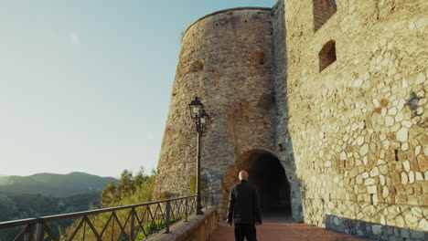 man tourist walks towards the defensive tower of a medieval castle in italy