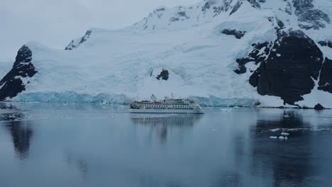 expedition cruise ship passing large iceberg in antarctica