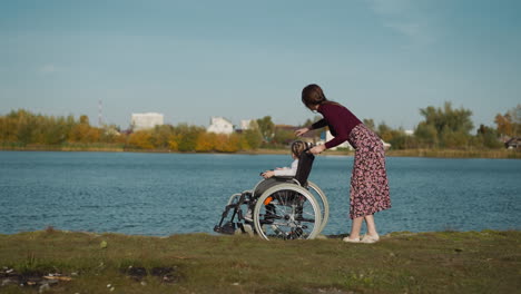 woman and child with spinal cord injury rest on river bank