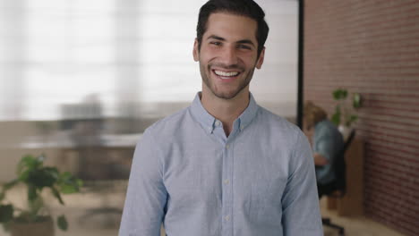 Retrato-De-Un-Joven-Empresario-Exitoso-Del-Medio-Oriente-Mirando-La-Cámara-Riendo-Alegremente-En-El-Fondo-Del-Espacio-De-Trabajo-De-Oficina