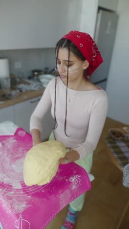 teenage girl kneading dough in kitchen