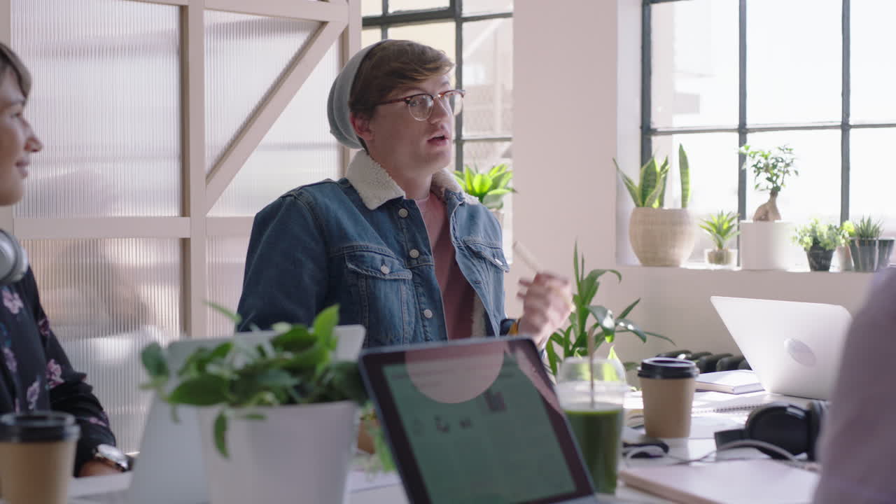 젊은 학생 그룹이 백인 팀 리더를 만나 창의적인 아이디어를 공유하고 대화를 즐기는 친구들이 현대 사무실 작업장에서 비즈니스 프로젝트를 논의합니다.