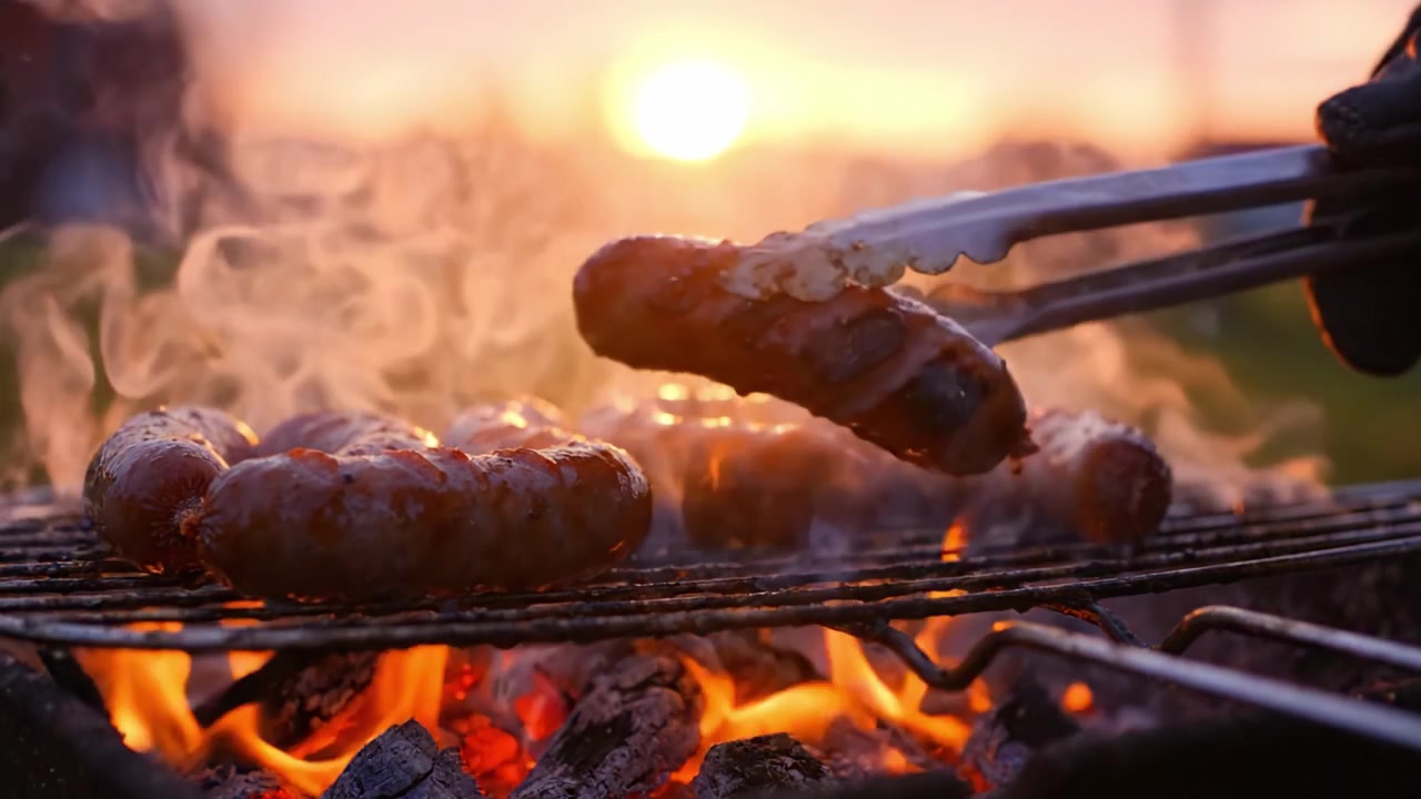 Deliziose salsicce che grigliano su carboni ardenti con un bellissimo sfondo al tramonto, catturando l'essenza della cucina all'aperto e delle riunioni estive.