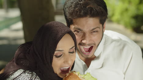 close-up of young muslim couple having fun, eating sandwich.