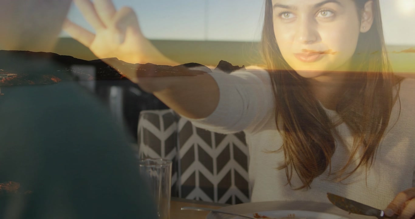 Couple after eating pizza reaching across restaurant table as sunset overlay boosting connection