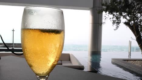 beer glass by pool with ocean view