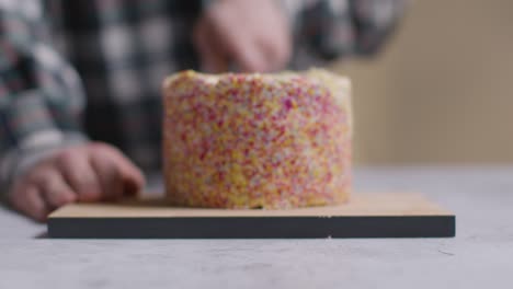 Nahaufnahme-Einer-Person-Zu-Hause,-Die-Ein-Stück-Vom-Regenbogenfestkuchen-Auf-Tisch-1-Schneidet