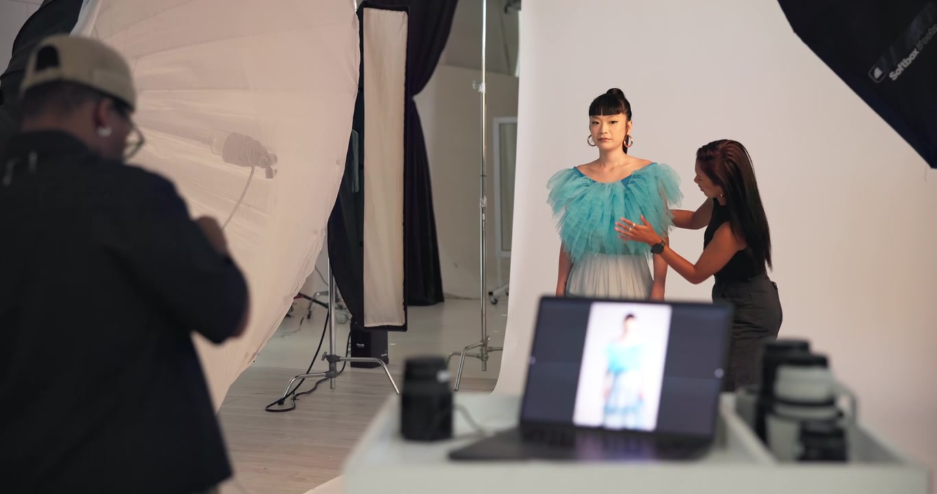 Fotografo di moda e stylist al lavoro con una modella in studio