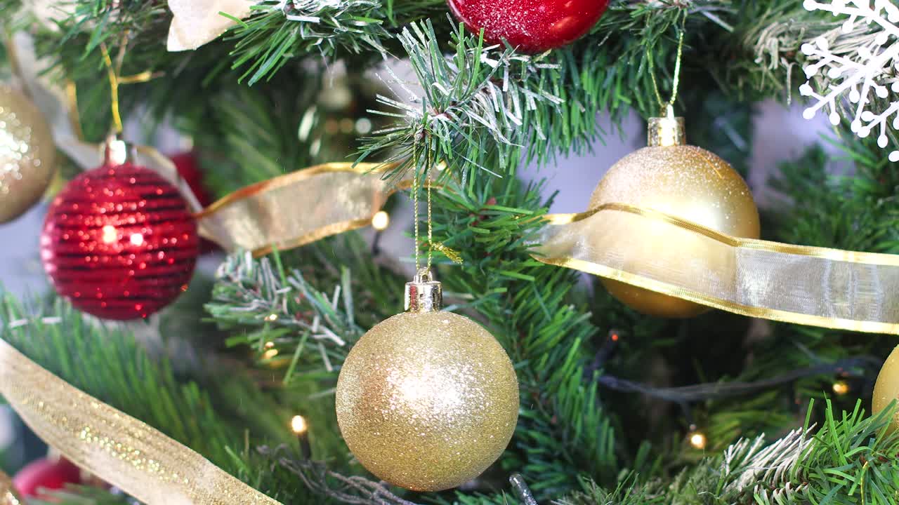 mano poniendo ornamento de brillo dorado en el árbol de navidad