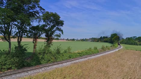 An-Aerial-View-of-an-Antique-Steam-Passenger-Train-Approaching-After-Going-around-a-Curve-Blowing-Smoke-and-Steam-Traveling-Thru-Fertile-Corn-Fields-During-the-Golden-Hour-on-a-Sunny-Summer-Day-1
