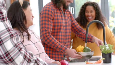 Happy-diverse-male-and-female-friends-preparing-food-together-in-kitchen