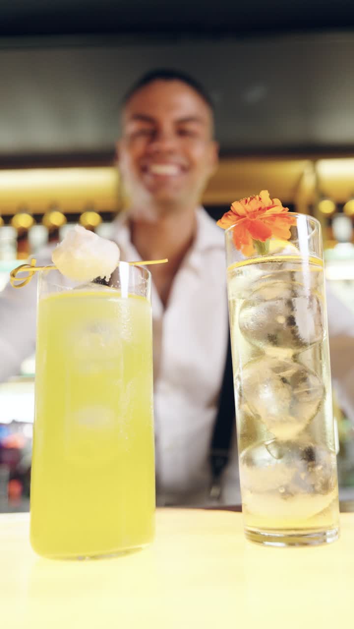 Two Refreshing Cocktails on a Bar Counter with a Smiling Bartender in the Background