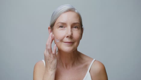 senior woman applying face cream