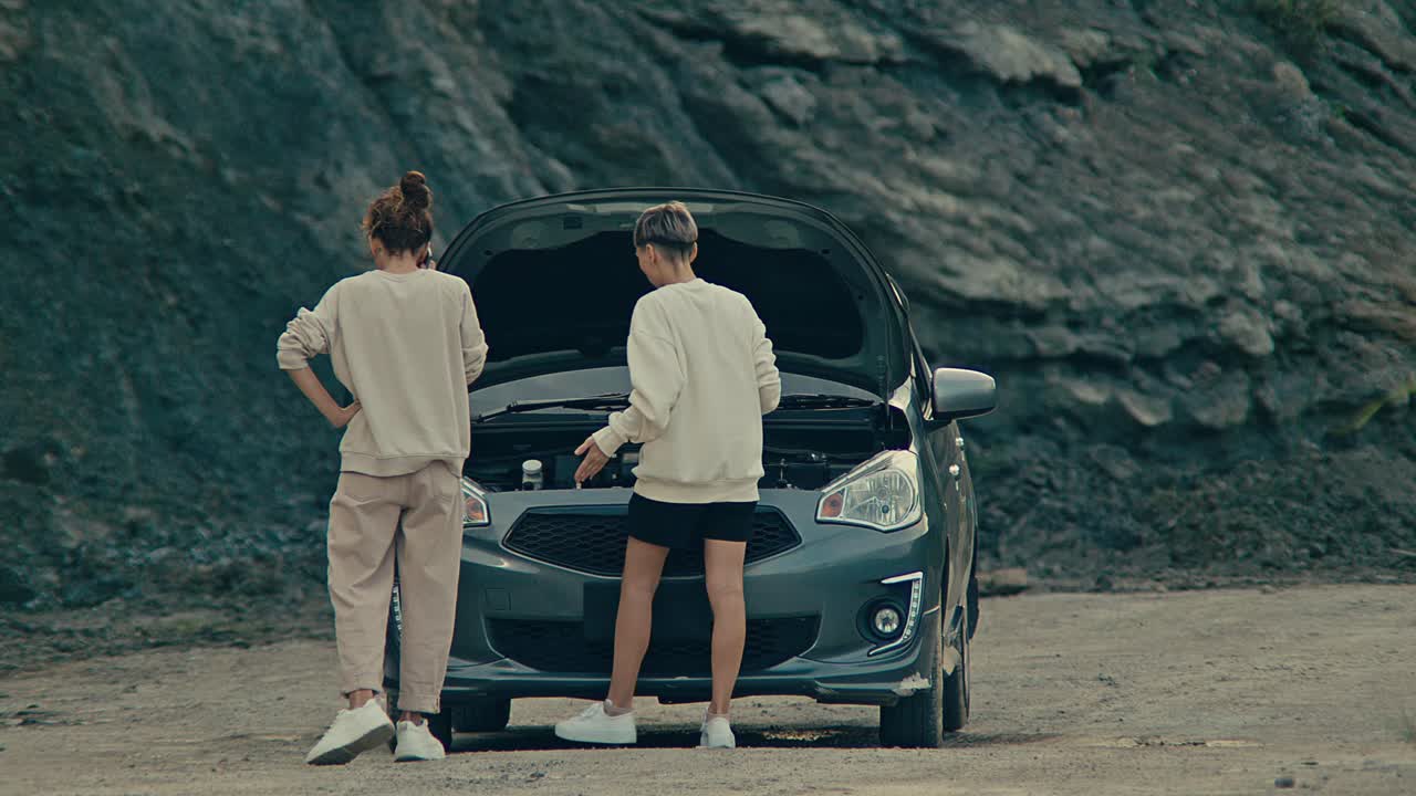 Two women facing car breakdown on a deserted road