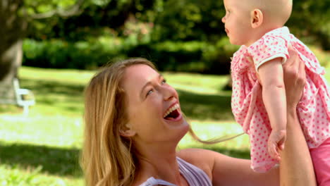 mother lifting her baby girl in the air