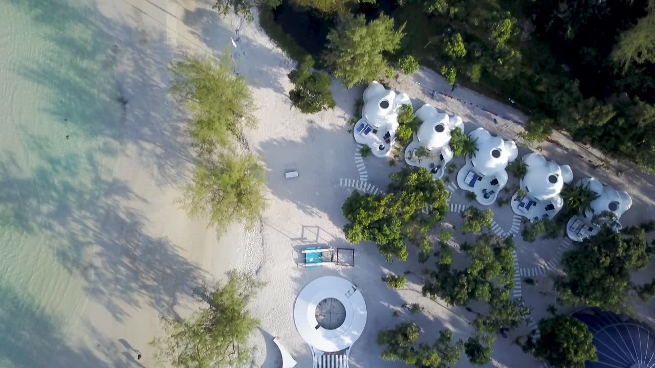 Aerial view of a beach with trees, sand, and buildings
