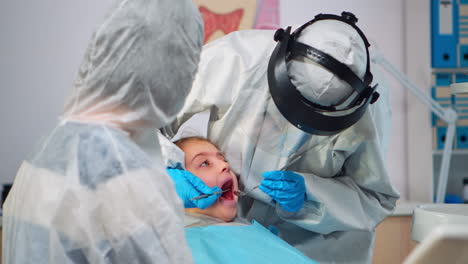 close up of dentist in coverall examining girl patient in new normal dental unit