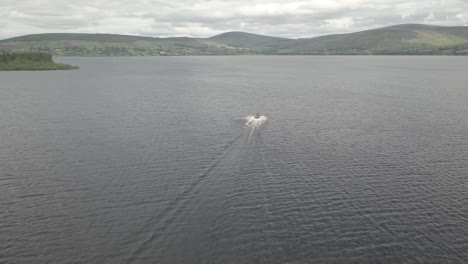 Lancha-Rápida-Navegando-Y-Dejando-Estela-En-La-Superficie-Del-Agua-Del-Lago-Blessedton-En-Wicklow,-Irlanda-Con-Cielo-Nublado