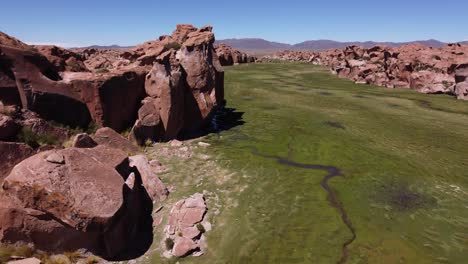 Flyover-hidden-lush-green-valley-in-Valle-de-las-Rocas-desert,-Bolivia