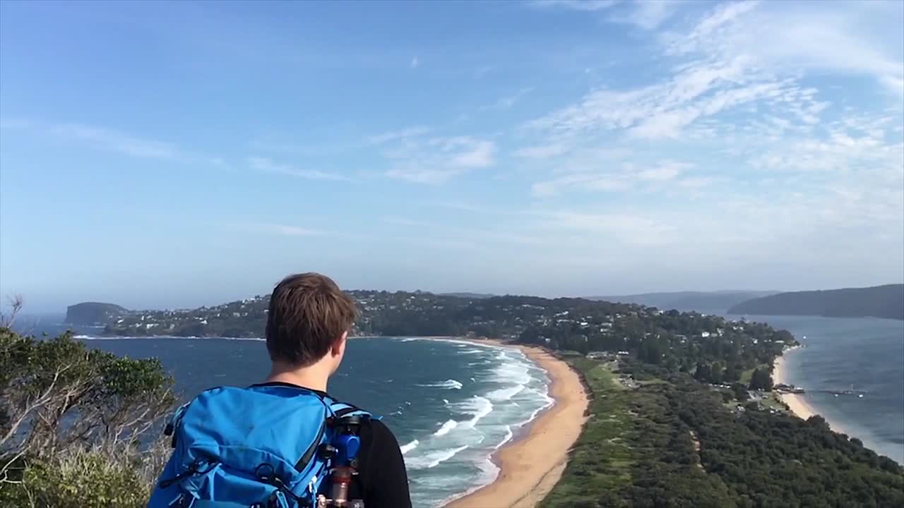 Young photographer with tripod and backpack looking out at the view while traveling in Sydney