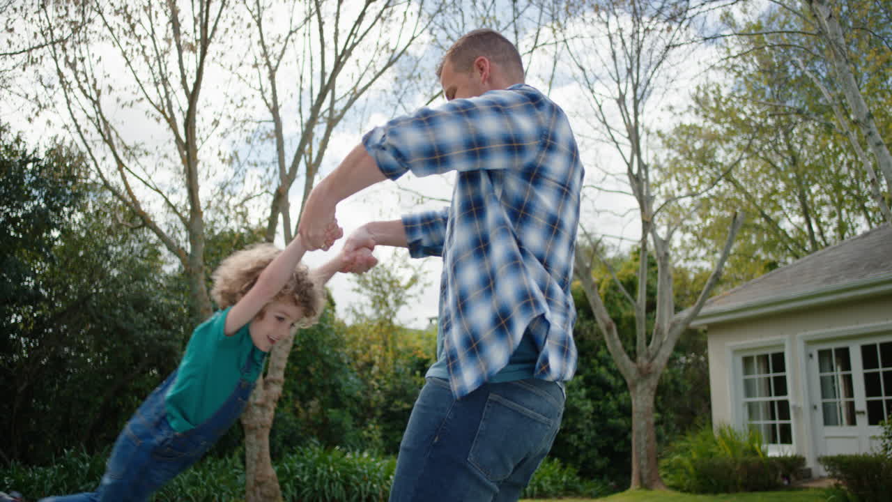 padre y hijo felices jugando juntos en el jardín del patio trasero niño pequeño feliz divirtiéndose con su padre sosteniendo al niño juguetón balanceando a su hijo disfrutando de la libertad de la infancia al aire libre 4k
