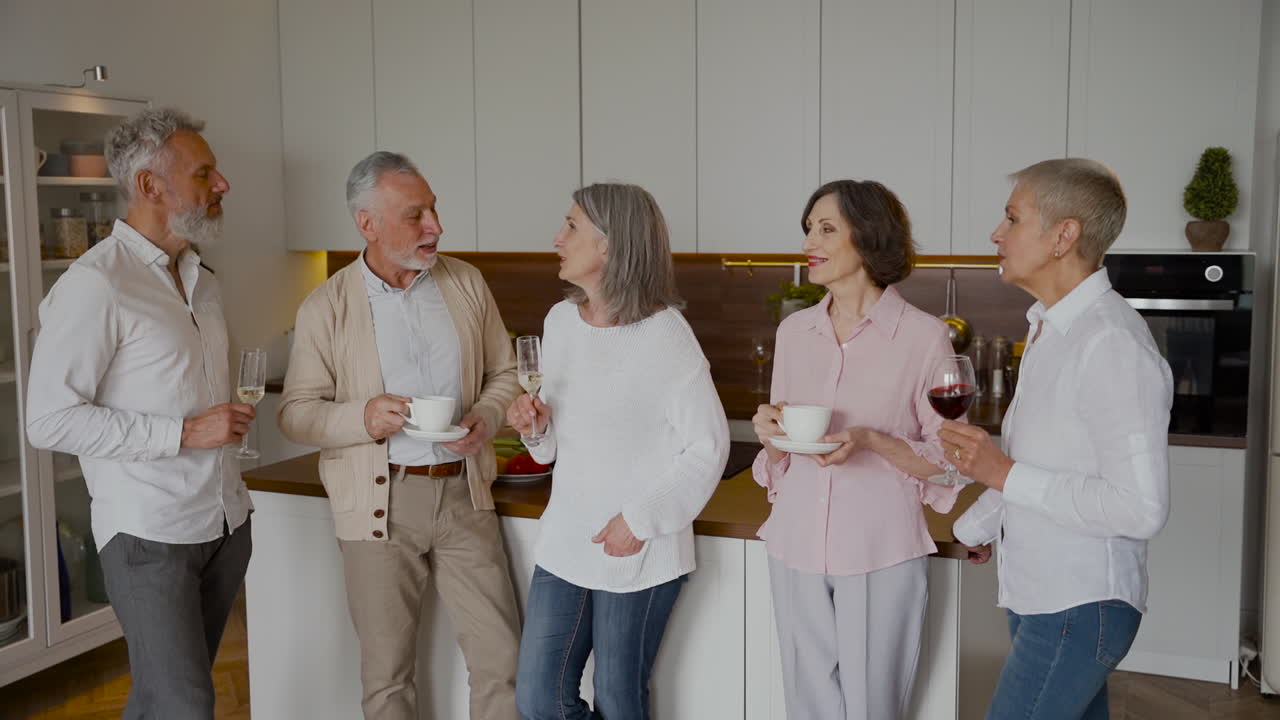 부엌에서 웃고 와인과 커피를 마시는 명랑한 선배들