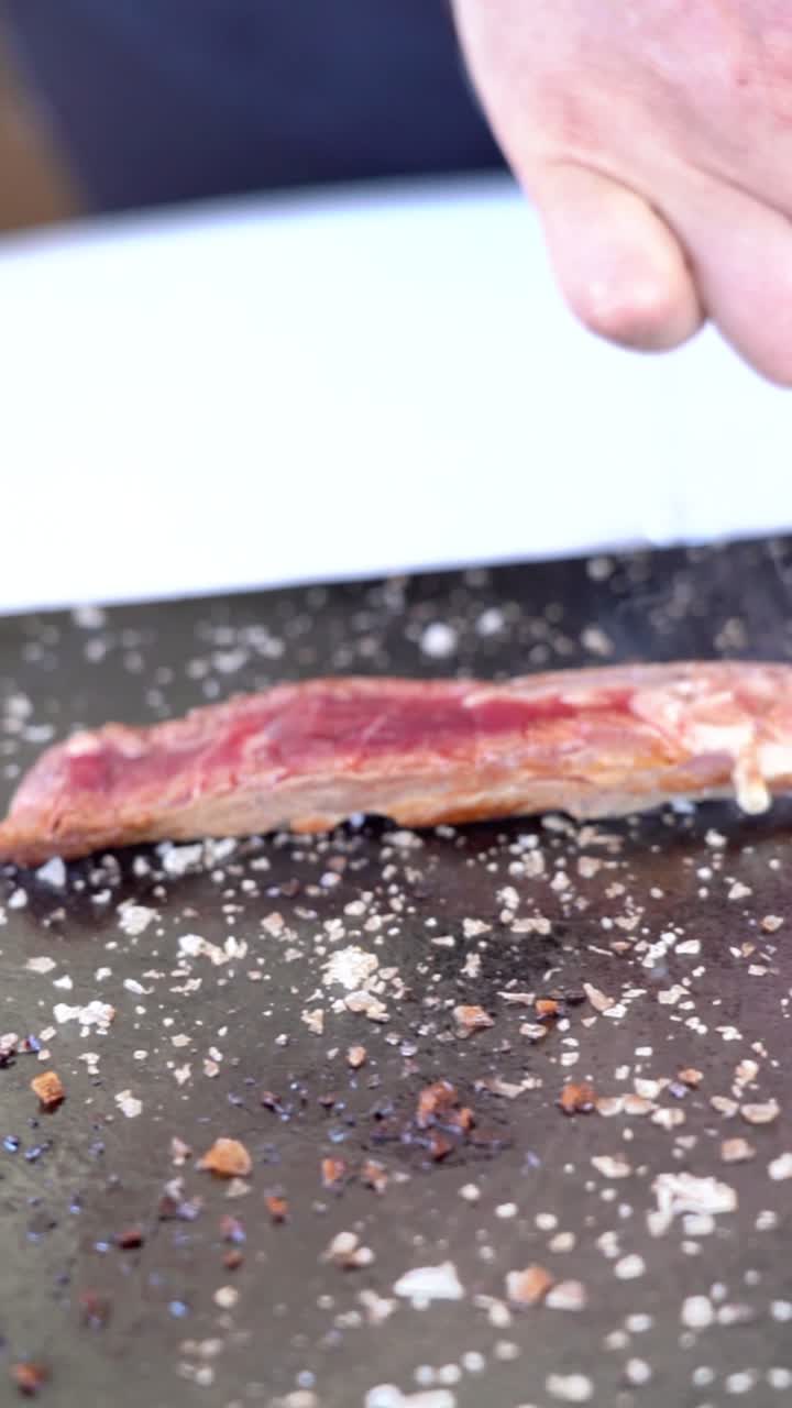 Un pezzo di carne su una superficie nera con un mucchio di sale sopra