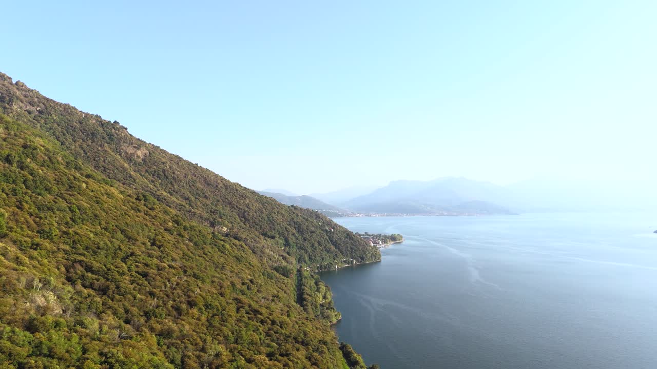 Fly sideways upwards, view of Lake Maggiore and hills with dense forests