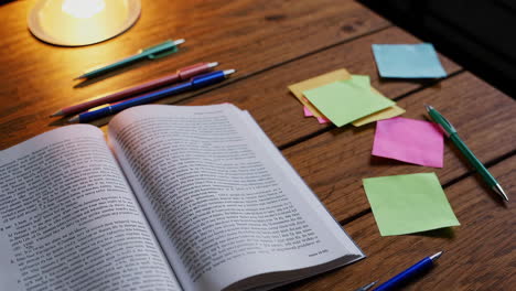 open book with sticky notes and pens on a wooden desk