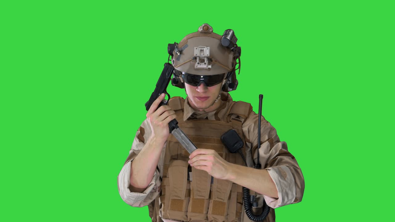 Soldato delle forze speciali dell'esercito che cammina e spara con una pistola su uno schermo verde, chroma key.