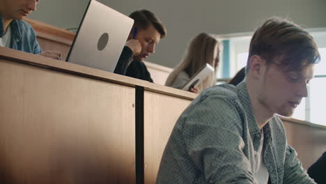 the camera moves through the audience where the students write a lecture on laptops and notebooks for professors in a large classroom of a university or college.