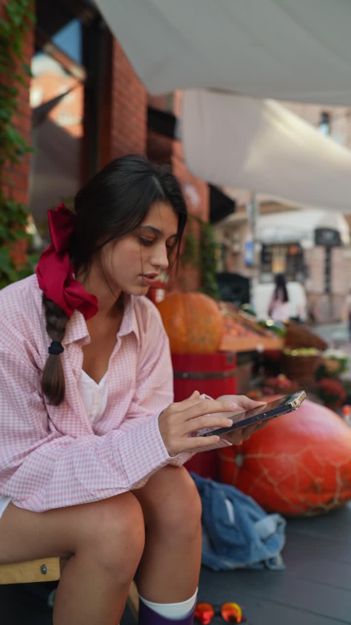 mujer joven usando el teléfono en el mercado al aire libre
