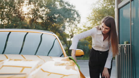 mujer limpiando un coche amarillo