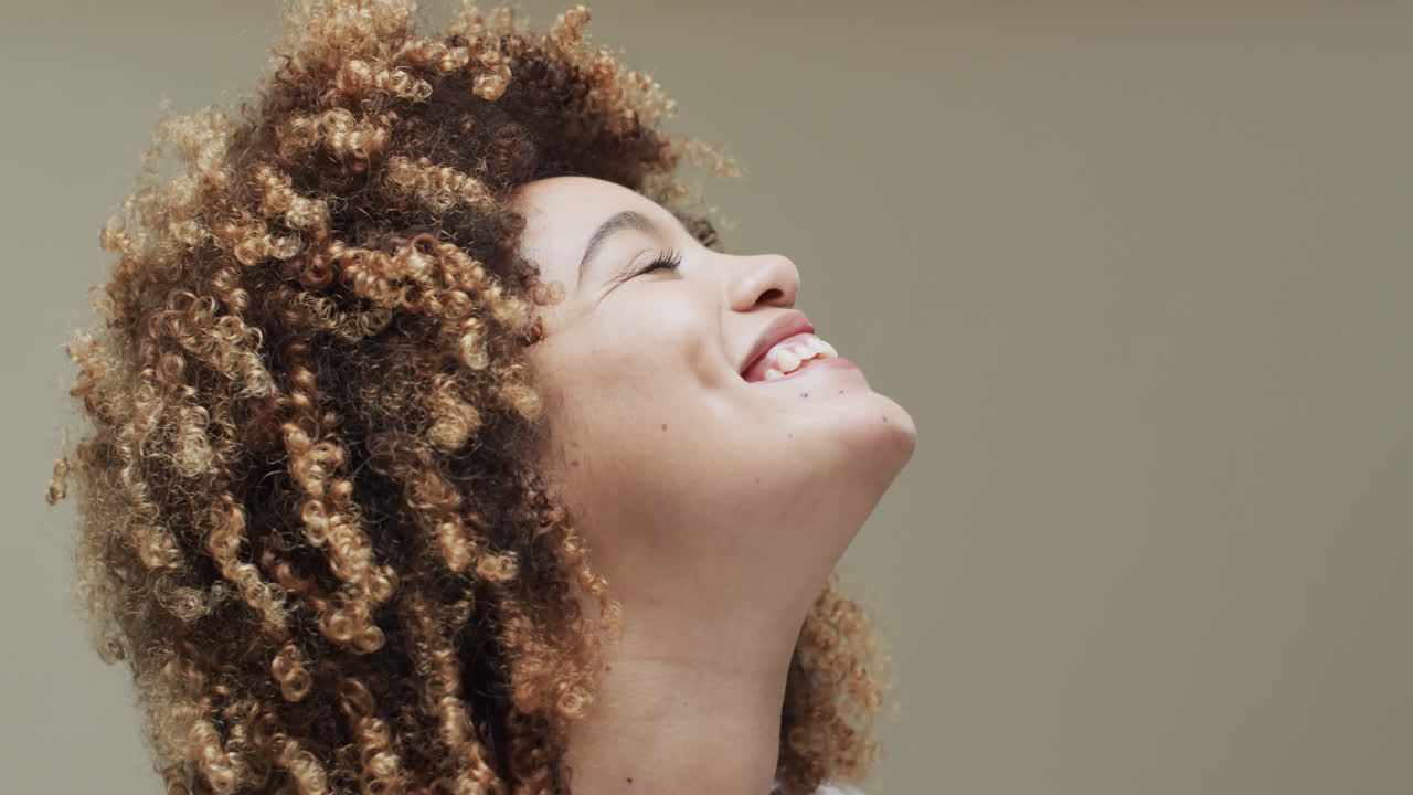 mujer biracial feliz con cabello oscuro en fondo beige con espacio de copia, cámara lenta