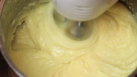 using an electric double whisk to mix cake batter in a metal bowl