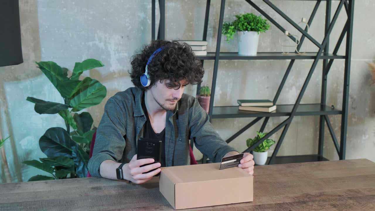 joven comprando en línea con tarjeta de crédito usando teléfono inteligente en casa