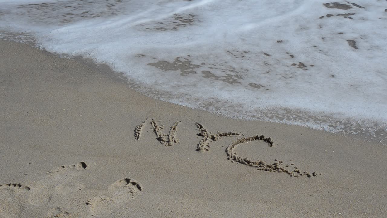 NYC escrito en la arena de la playa. Nueva York, una inscripción en la arena