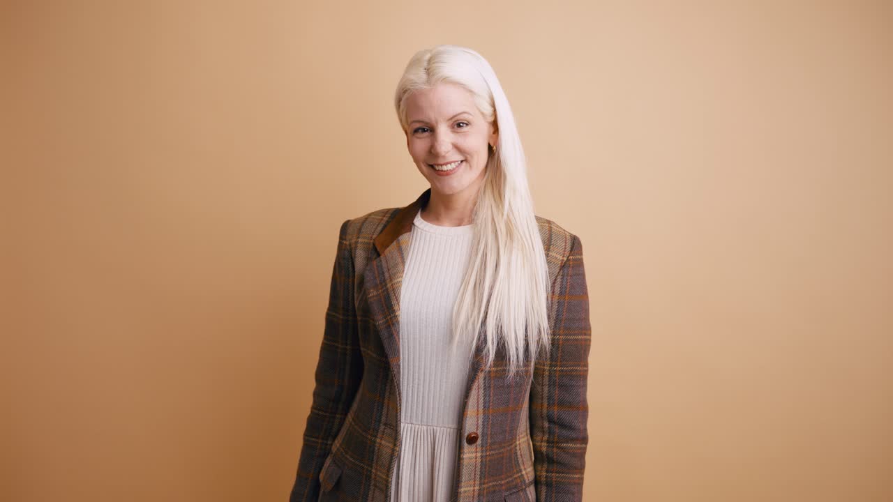 Donna bionda sorridente in blazer a quadri che guarda in camera