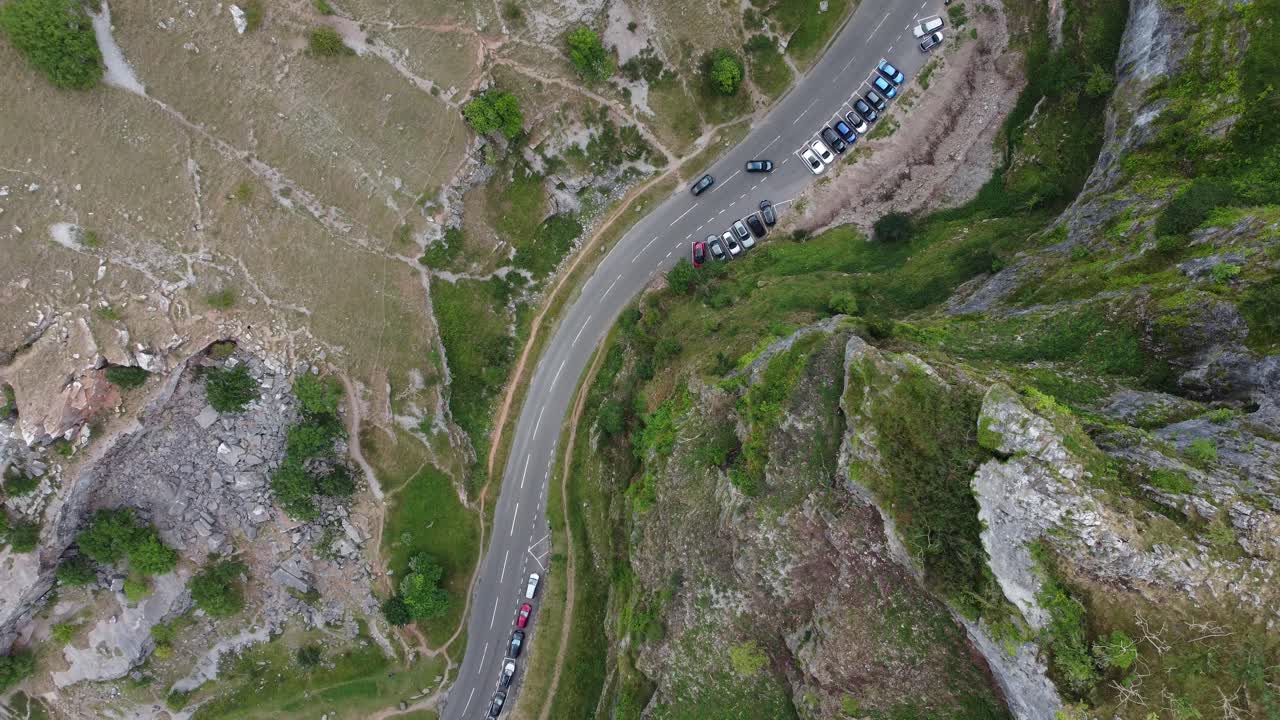 Static top down aerial view of cars driving past a car park at Cheddar gorge in the Mendip Hills, Somerset, UK