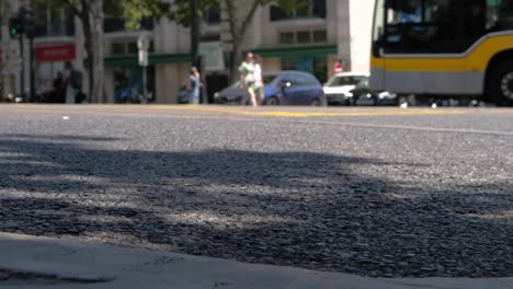 Asphalt-Focus-on-foreground,-blurred-trafic-and-people-in-background,-Slow-motion